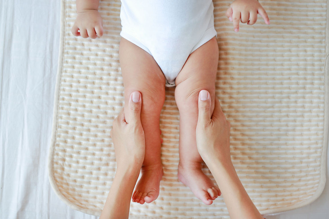 Mother doing massage for leg infant baby.